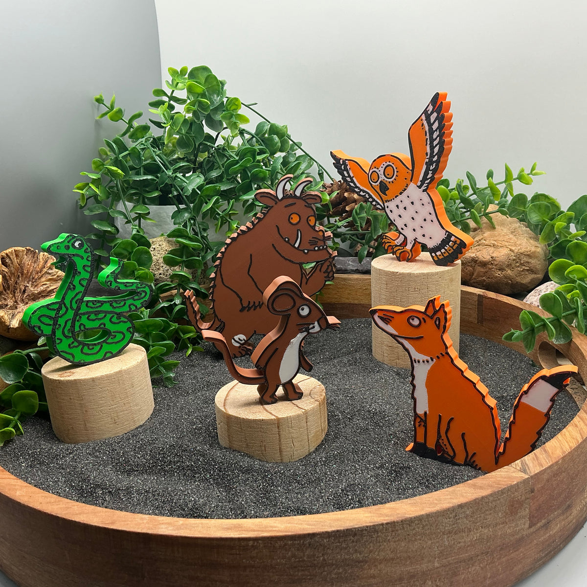 Forest monster, mouse, owl, snake and fox figures standing in a sand tray