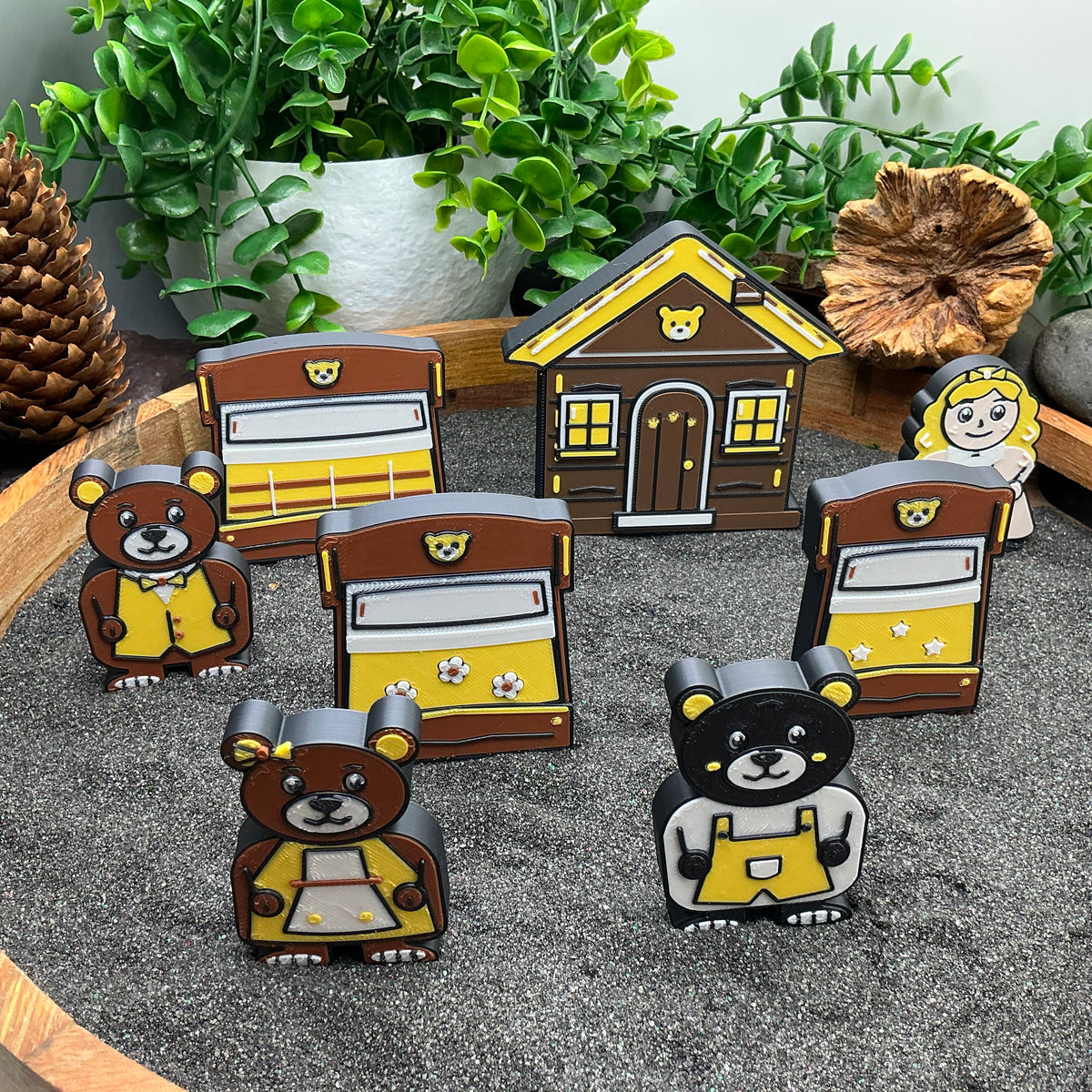 Small Goldilocks and bear characters standing among three bed pieces and a cottage