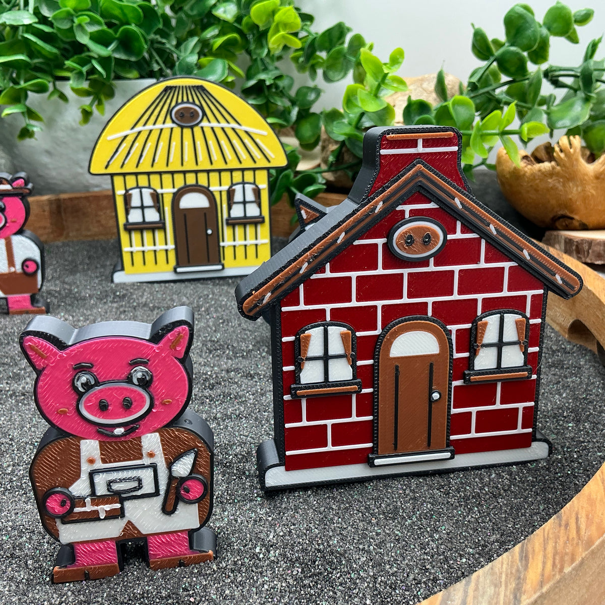 Small pig figure standing beside the red brick house with the straw house behind