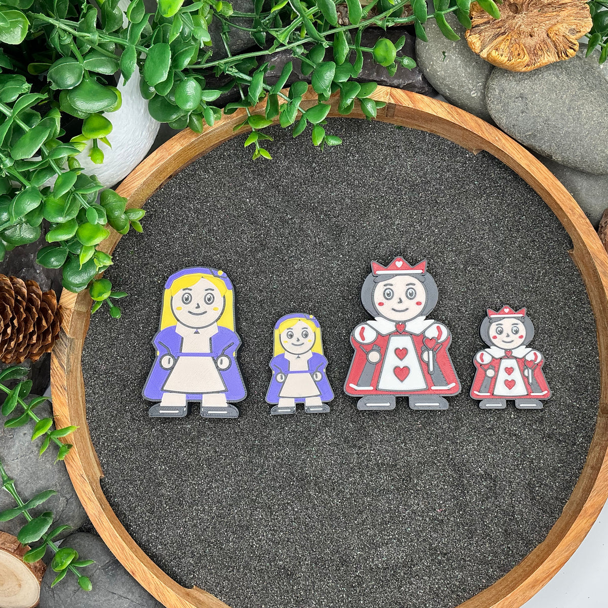 Large and Small blonde-haired Alice figures beside both sizes of the Queen of Hearts