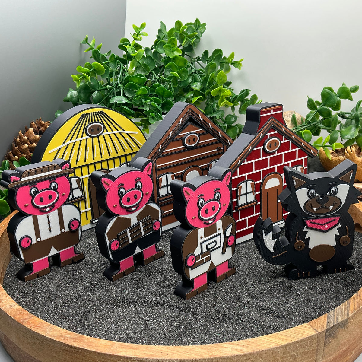 Three Large pig figures and the wolf standing in front of the straw, stick and brick houses