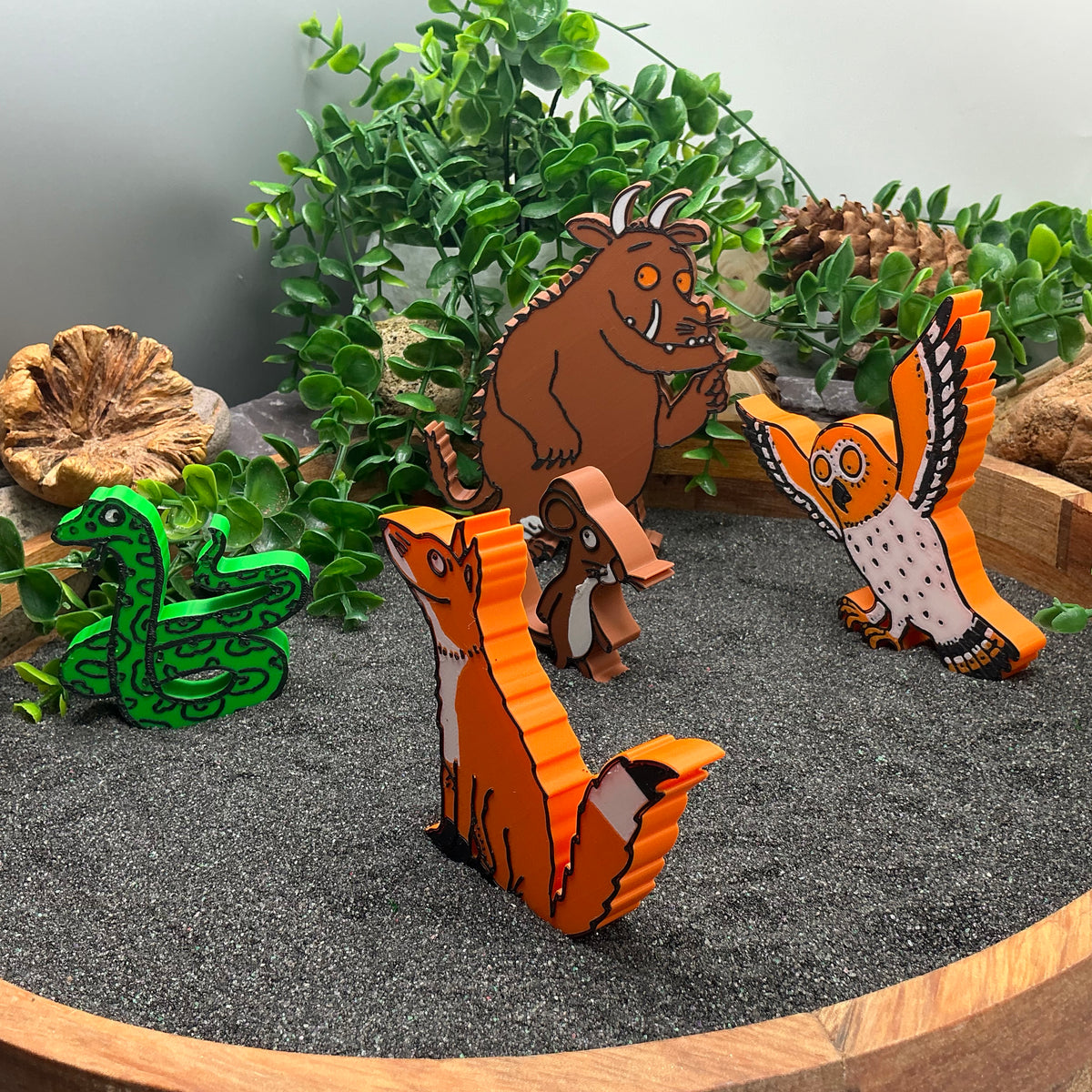 Fox figure standing in sand with the other woodland characters behind