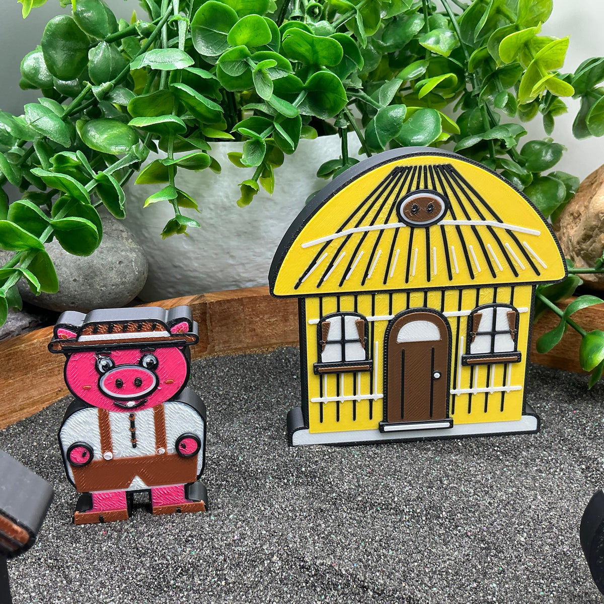 Small pig figure standing beside the yellow straw house