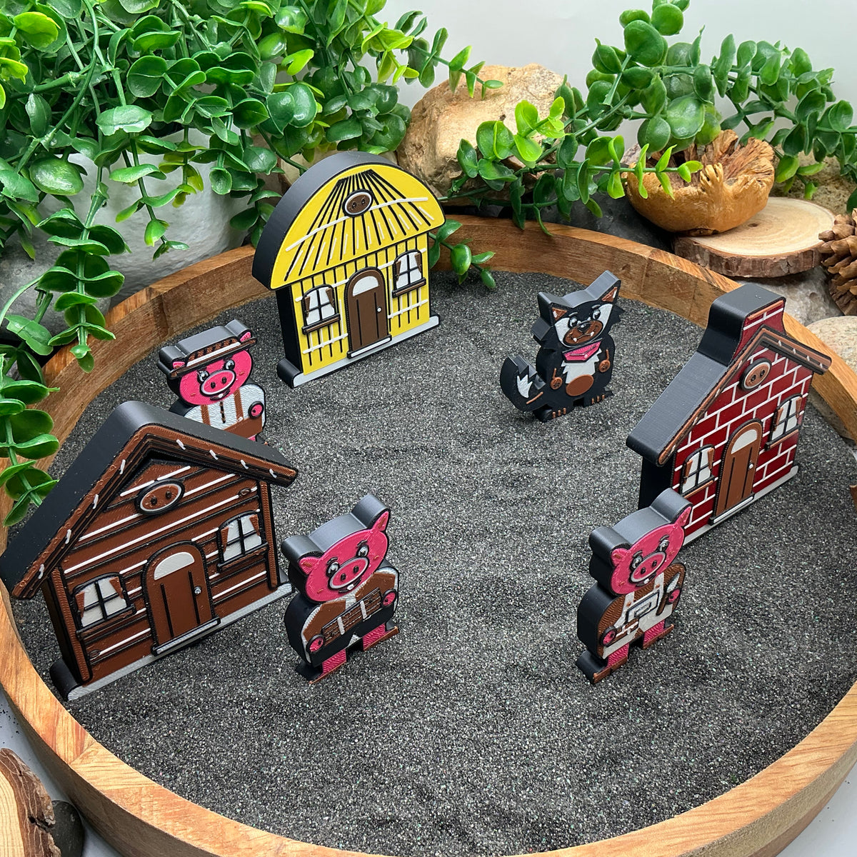 Side view of the Small Three Little Pigs story characters and houses standing in sand