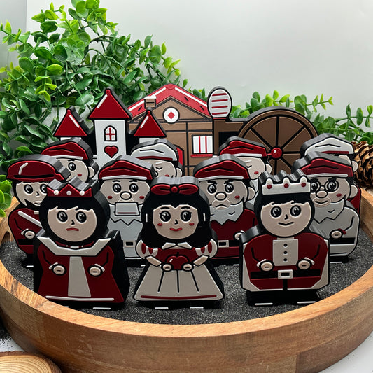Snow White, seven dwarfs, queen, prince and huntsman standing with their castle, cottage and spinning-wheel scene props
