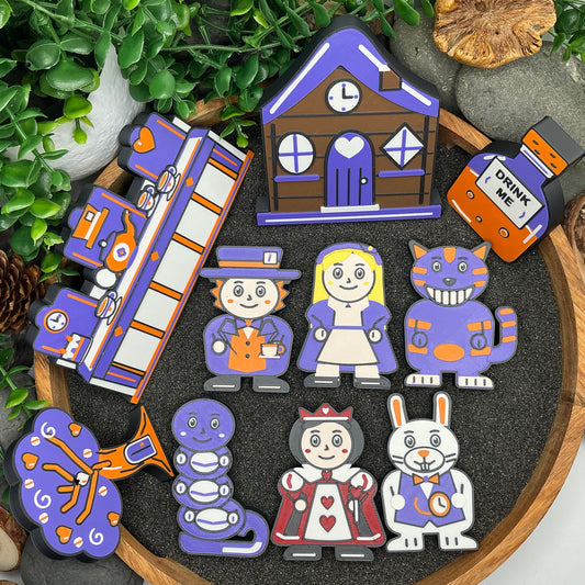 Large ten-piece Alice in Wonderland story set laid flat, with blonde Alice, five other characters, cottage, tea-party scene, tree and Drink Me bottle