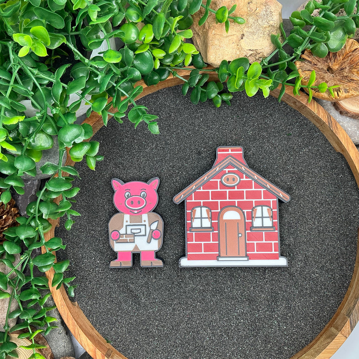 Small pig character beside the red brick house, laid flat in sand