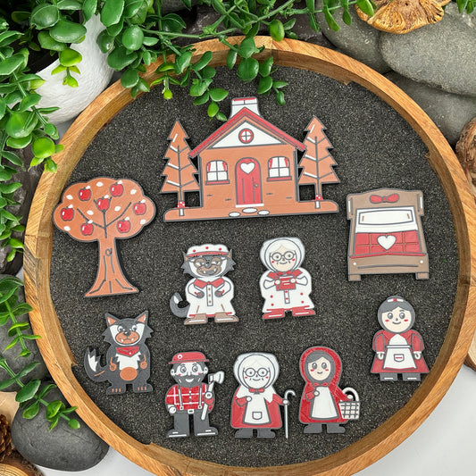 Small ten-piece Little Red Riding Hood story set laid flat in a wooden sand tray, including Sly Wolf, Bedtime Grandma, Red's mother and Grandma's bed