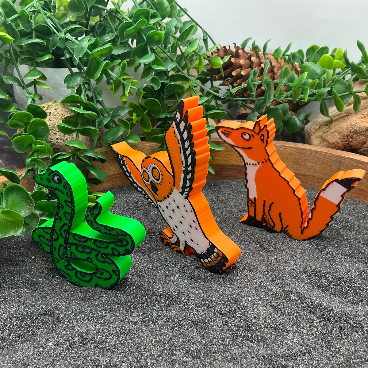 Snake, owl and fox figures standing in sand