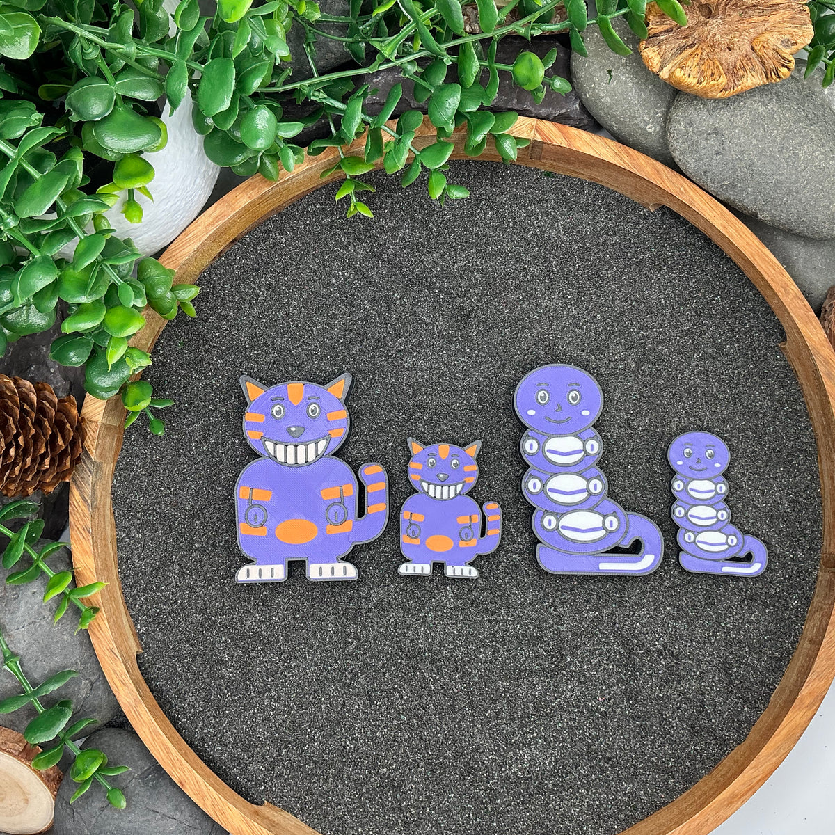 Large and Small Cheshire Cat and Caterpillar figures laid out side by side