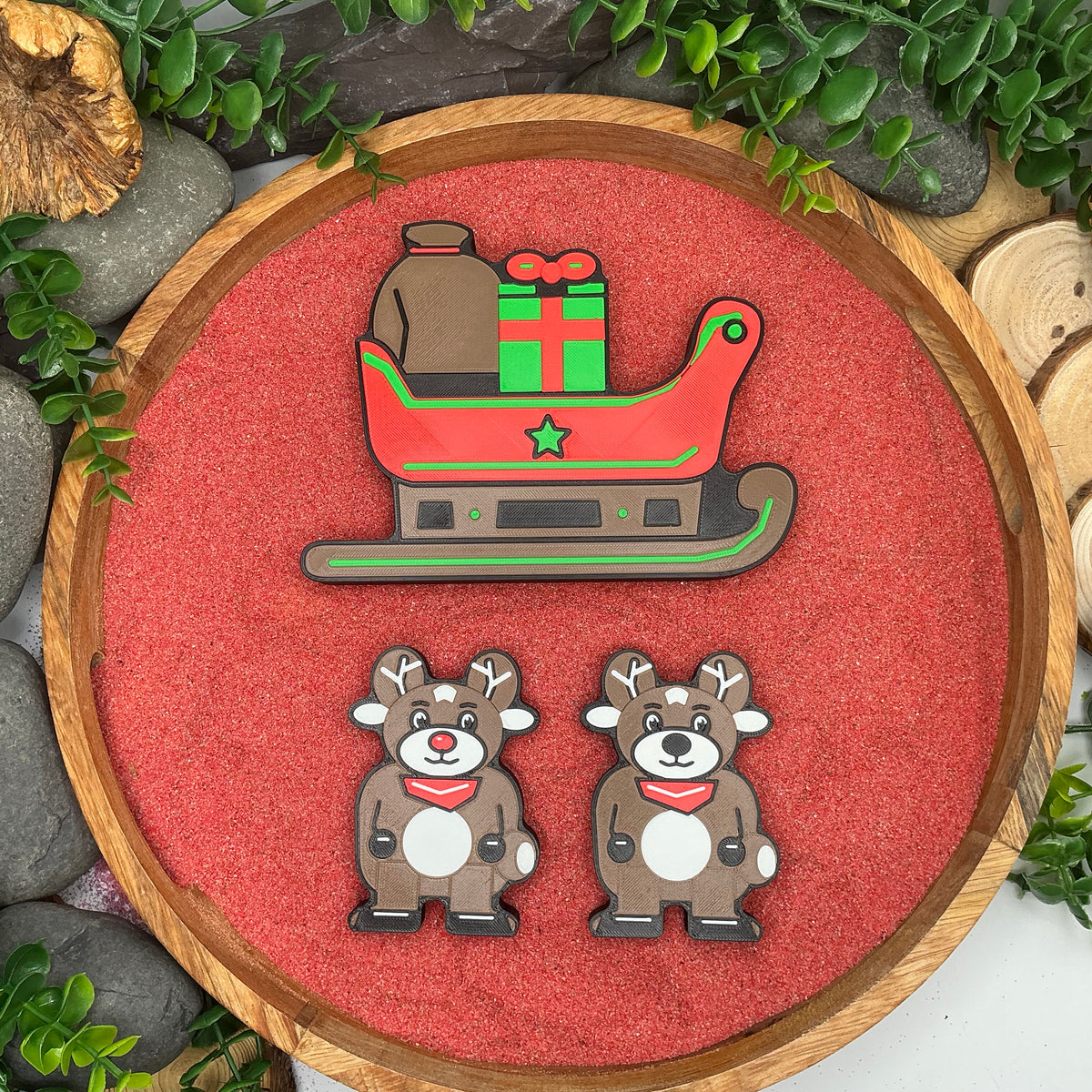Christmas sleigh with attached gifts and two reindeer, including one with a red nose, laid flat in a wooden tray
