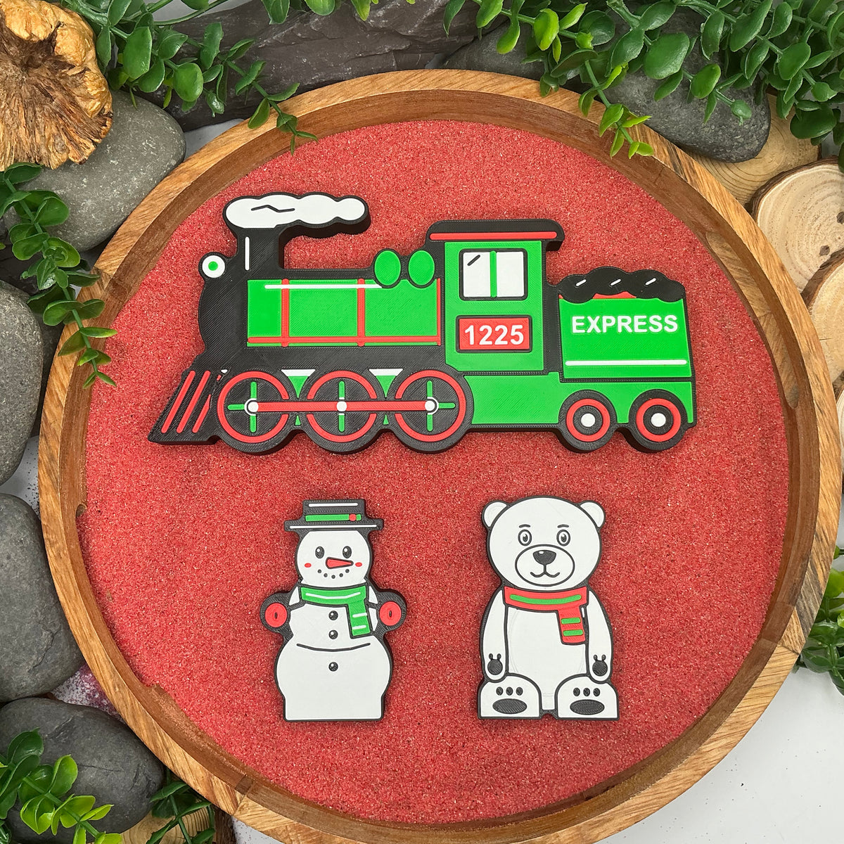 Christmas express train, snowman and polar bear laid flat in a wooden tray with red sand
