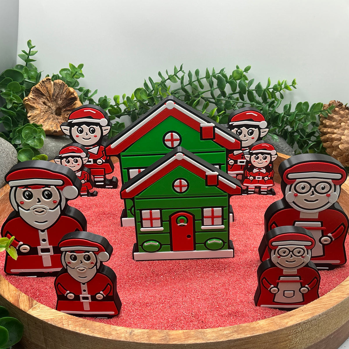 Large and Small Claus figures, elves and Christmas cottages standing together