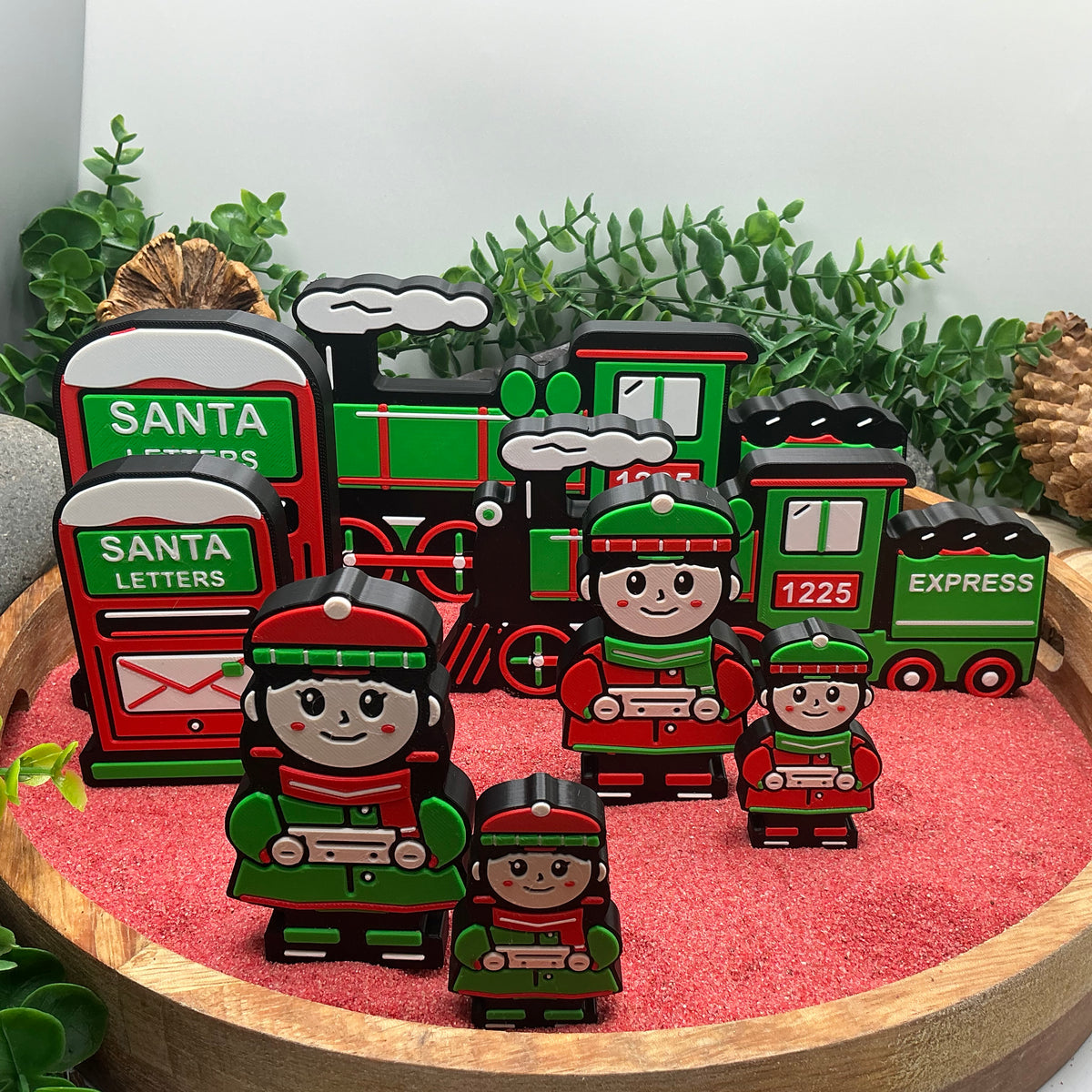 Both sizes of the Christmas train, post box and winter passenger figures standing together